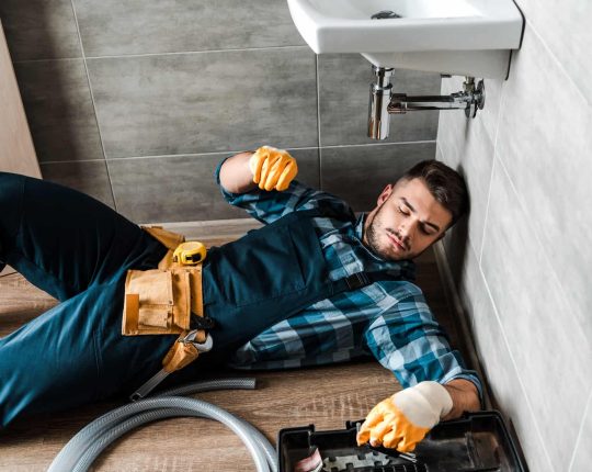 bearded-handyman-lying-on-floor-near-toolbox-in-bathroom.jpg